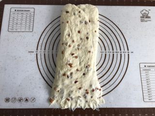 面包机版红枣果仁面包,将面团90度转向后，擀成长条形，底部压薄。