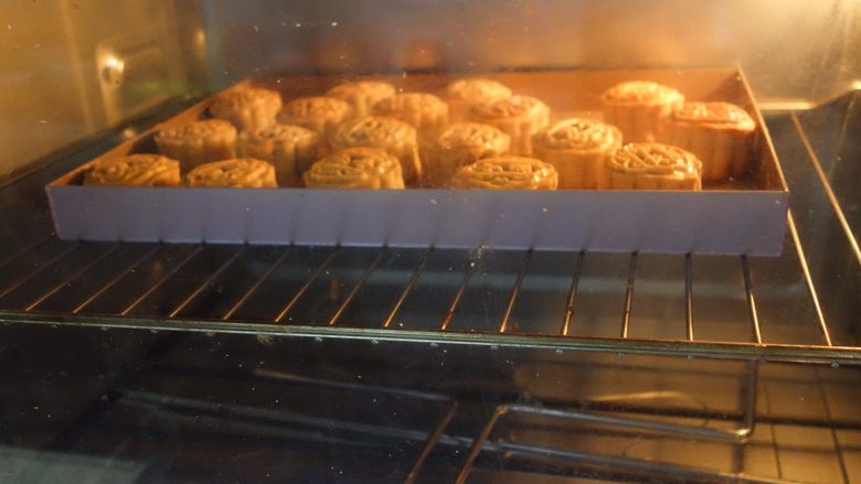 广式莲蓉蛋黄、豆沙蛋黄月饼制作方法,烤箱预热180度，中层，上下火，喷一点水在月饼上烤5-7分钟定型。