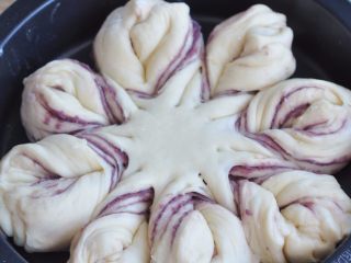 花朵紫薯面包,将相邻的两个面条朝相对的方向扭两圈，再将扭好的花朵尖处捏合紧。烤箱里放一碗开水，将面团放进去发酵40分钟。