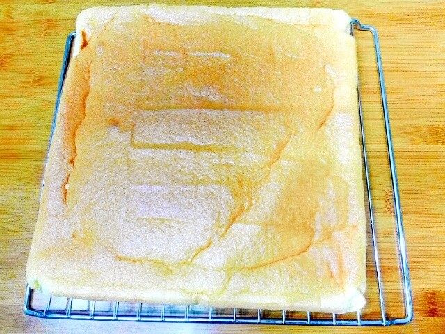 小四卷(后蛋法）,烘烤结束取出烤盘轻摔一下，把蛋糕卷连同油纸移至晾网架上，轻轻撕去油
纸，再虚盖在蛋糕上。(如果是正卷的话，就是正面向上，反卷就是贴油纸的那面