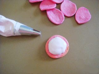 出水芙蓉饼干,取适量棉花糖装入裱花袋里，揉几下排除空气，棉花糖会更细腻，代替糖霜用来固定饼干。（最小号圆口裱花嘴）把棉花糖挤在饼干托上。