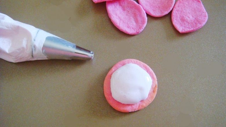出水芙蓉饼干,取适量棉花糖装入裱花袋里，揉几下排除空气，棉花糖会更细腻，代替糖霜用来固定饼干。（最小号圆口裱花嘴）把棉花糖挤在饼干托上。