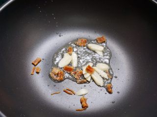 肉燥虾仁豆腐,下少量油，将干瑶柱和蒜片下锅干煸到发出香味。