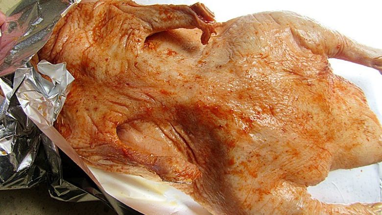 家庭自制脆皮蜜汁烤鸭,腌好的鸭子取出，放在阴凉的地方自然风干晾至少5小时，至表皮干燥，紧缩发亮，把苹果切成几块塞进鸭肚子里，可以用牙签将开口固定一下。将容易烤糊的