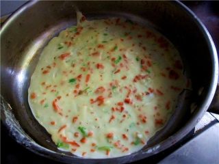 胡萝卜鸡蛋饼,用勺子盛适量面糊倒入锅中，让锅子倾斜并转动，让蛋糊液在锅中流动平整