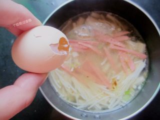 金针菇馓子汤,把火腿肠丝放入锅内，打入蛋液