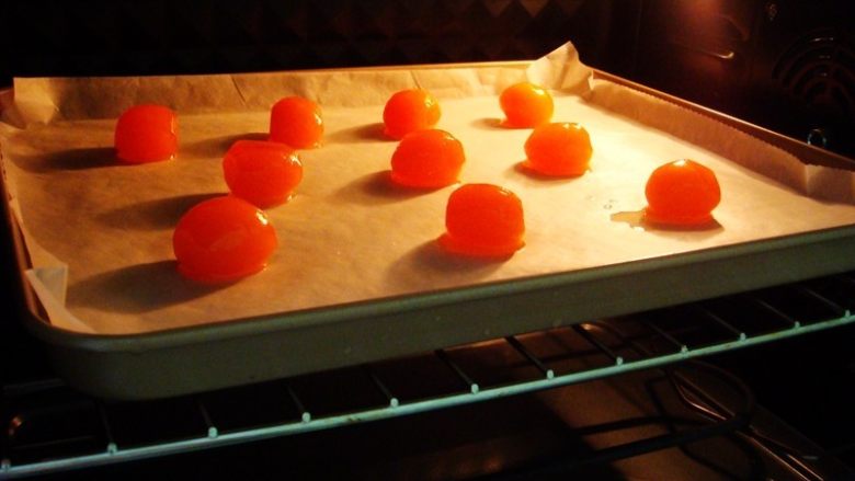 莲蓉蛋黄冰皮月饼,烤盘里铺上油纸，放入所需用量的蛋黄。烤箱提前预热：上下180度，放中层，烤8分钟取出，晾凉备用。