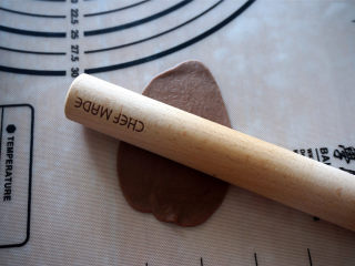豹纹吐司,取一个可可小面团，擀成椭圆形面片，沿着长边卷起来，然后用手搓至比吐司盒稍微短一些。