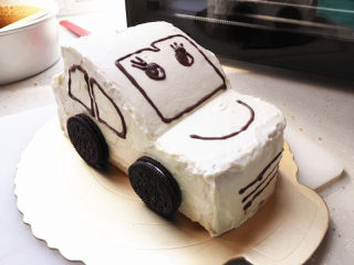 小汽车蛋糕,巧克力隔水融化后装入裱花袋里，剪一个小口，画上小汽车的眼睛，嘴，车窗等，奥利奥饼干放在小汽车的轮子位置，