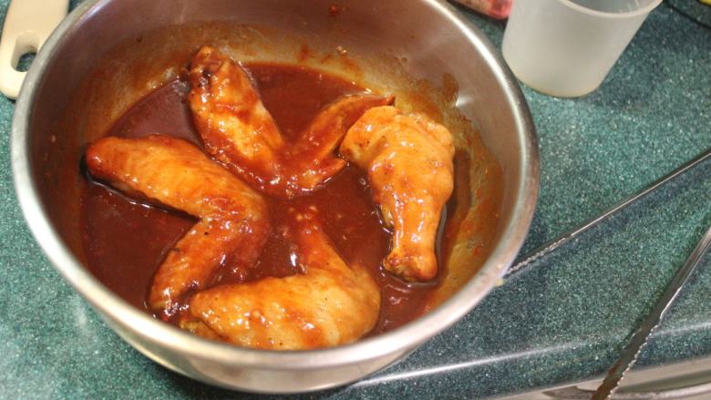 可乐辣味鸡翅,将烤好的鸡翅放入沾裹酱汁。