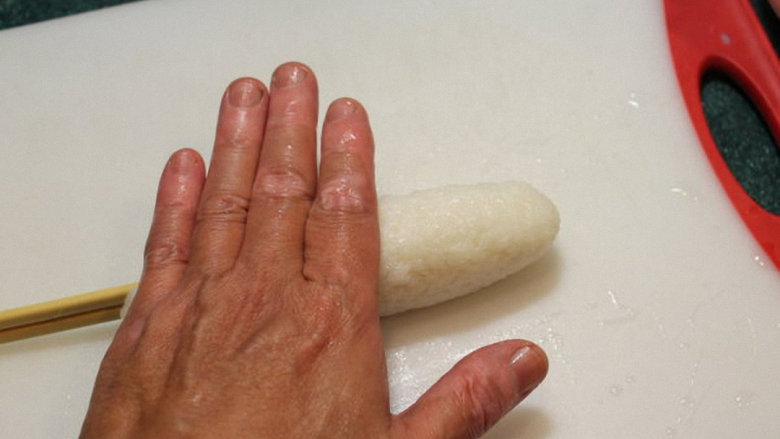 烤米卷,将饭条放于钻板上，用手掌滚压成结实长条型。