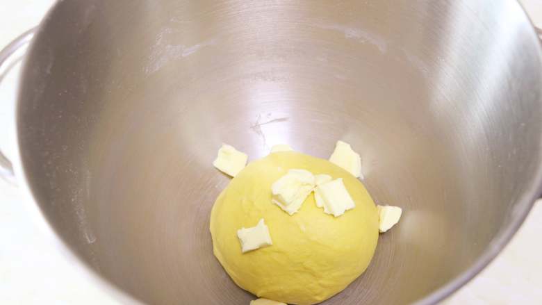 南瓜肉松芝麻包,启动厨师机揉面，待面团揉至光滑有韧性时，加入室温软化的黄油