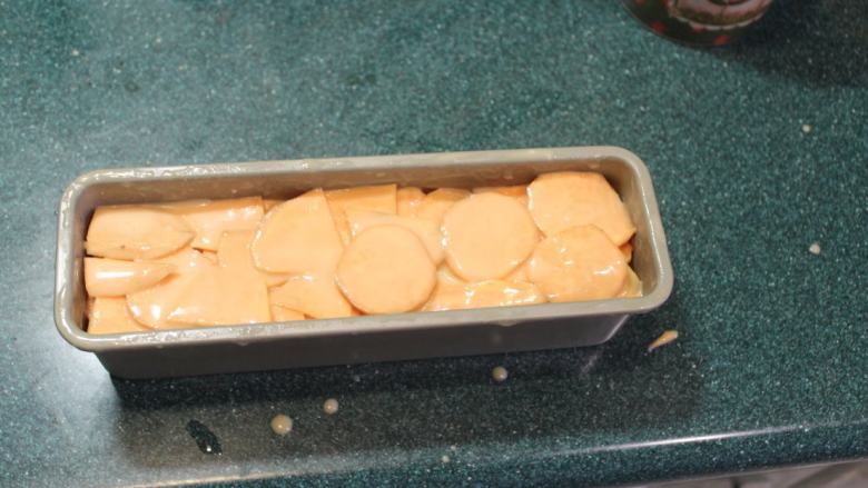 千层地瓜蛋糕,将地瓜片层层迭迭的摆入烤模。如果烤模底部不能分离，要垫上一层烤盘纸才容易脱模。