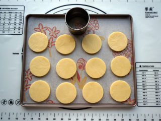 愤怒的小鸟糖霜饼干,取出冷冻至硬的面片，用圆形饼干模具印出饼胚，放入烤盘中。
