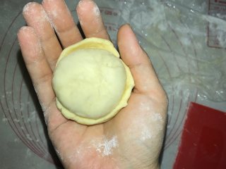 菠萝包,一手拿酥皮，一手拿面团，酥皮放在面团上，将酥皮慢慢包裹在面团上