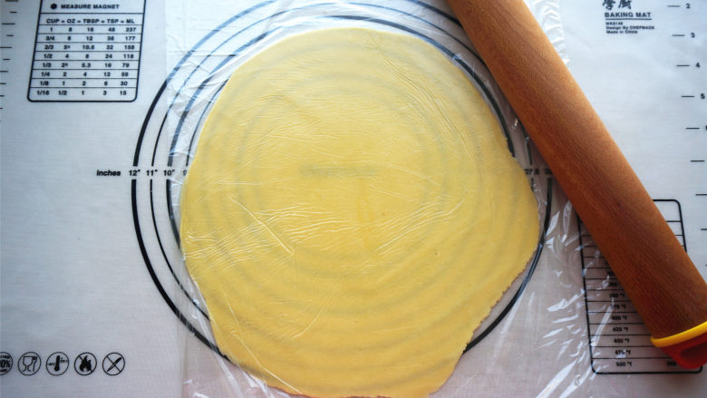 橘子酥塔,将面团放入两层保鲜纸中间，擀开成2毫米厚的圆形面片。
