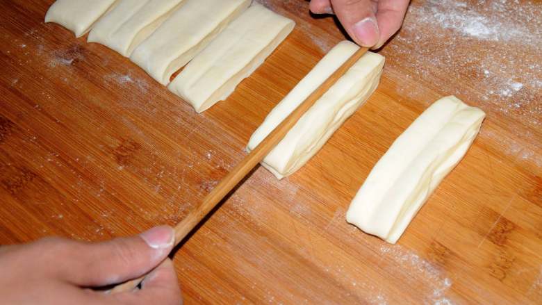 家常油条怎么炸 老师傅分享的方子 让你在家轻松做出好吃的油条,每两个条叠在一起，用筷子在中间压一下。