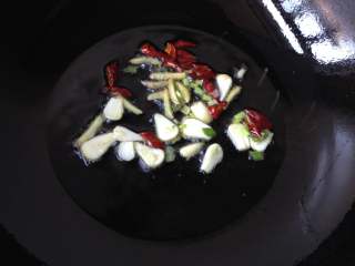 辣酱炒螺蛳,油热后下入姜丝、蒜片、辣椒段和葱花（1/3）爆香