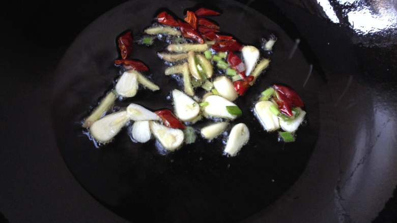 辣酱炒螺蛳,油热后下入姜丝、蒜片、辣椒段和葱花（1/3）爆香