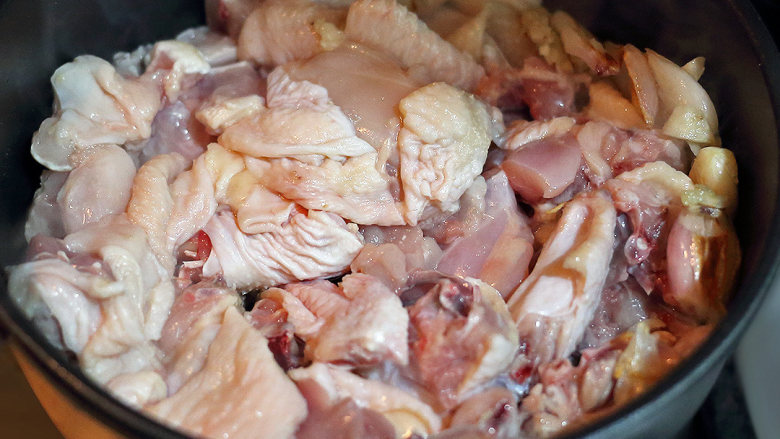 红葱头沙姜焗鸡,待蒜头表面轻微有点焦黑，倒入鸡块，加盐，来回翻动，烫1分钟，去掉鸡肉多余水分
