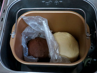松软绵绵滴【可可双色面包】,将两份面团放到面包机内，用保鲜膜隔离开