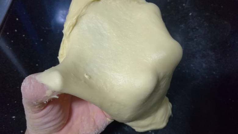 面包入门基本功之黄油面包卷,如此大约十多分钟后，面团逐渐均匀、细腻、光滑，可以撑开，但还没到手套膜的阶段。这一阶段的揉面需要十多分钟。