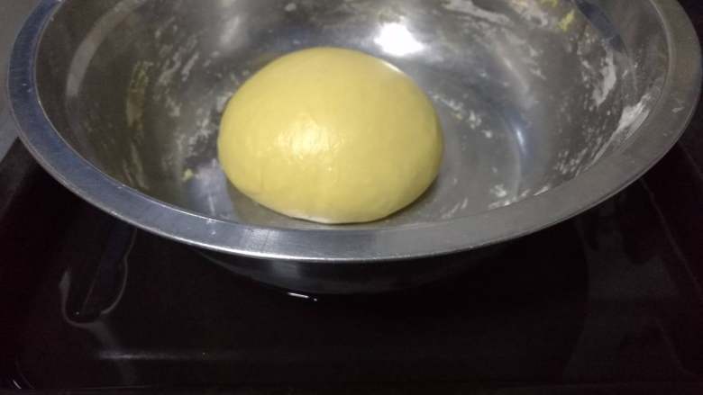 面包入门基本功之黄油面包卷,用两手轻轻将面团扒至近处，使面团表面鼓胀起来。然后面团放在面盆里，盆放在加了热水的烤盘里。
