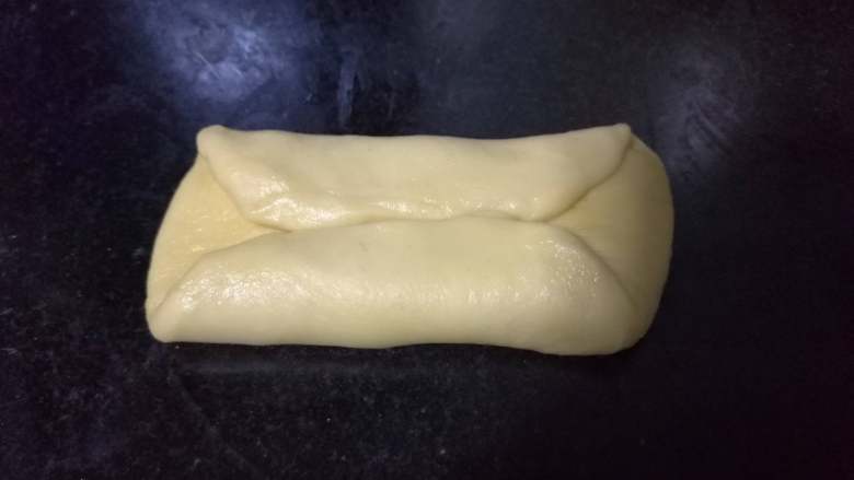 面包入门基本功之黄油面包卷,取出一个个小面团，先按扁，然后将较远端向下折三分之一，近端向上折三分之一。