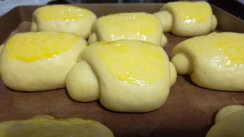 面包入门基本功之黄油面包卷,取出面包卷，将刚才剩下的蛋液均匀地刷在面包表面。烤箱预热至220度后，放入面包烤15分钟。