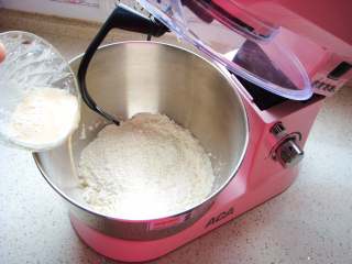 全麦烤馅饼,盆里倒入高筋面粉和全麦粉。酵母粉用适量温水搅拌融化，倒入面粉中。