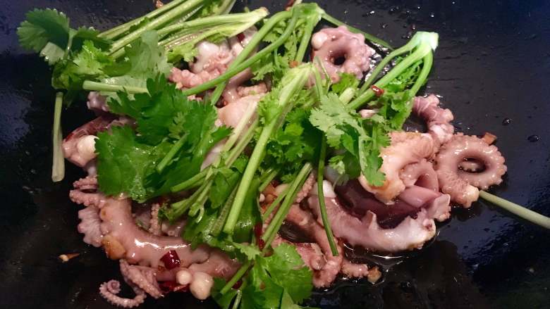 一锅出海鲜烩,同时，在另一口炒调料的锅里倒入小章鱼和香菜梗，利用剩下的料汁拌一下（不用开火）。