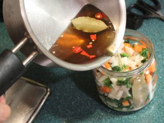 日式腌萝卜,将压好的萝卜和萝卜叶放入煮过消毒好的玻璃罐中，趁热将腌汁倒入萝卜罐。