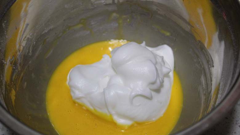 抹茶双色蛋糕卷,取三分之一的蛋白霜和蛋黄糊翻拌均匀