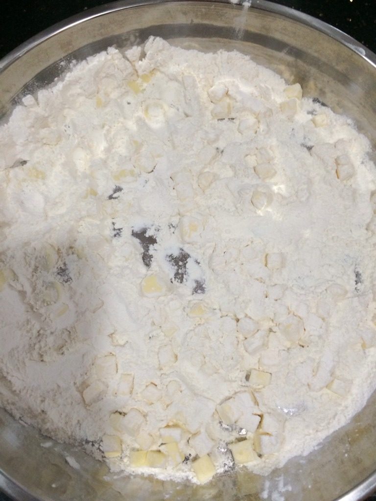 自制苹果派,2-将低粉和盐，均匀倒在黄油丁上（如图）后用刀切啊切……直至黄油和粉类变成松散的沙粒状