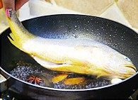 家常烧黄花鱼,提着鱼尾将鱼的一面在汤里滚半分钟，然后翻面，将鱼放入锅内