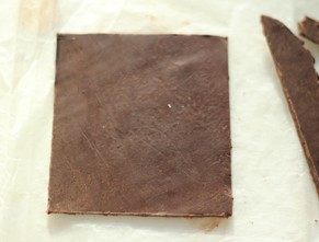 浓情巧克力礼盒,取一块巧克力材料，用油纸覆盖住，用擀面杖擀成不算薄的大片，量好尺寸，切割成正方形