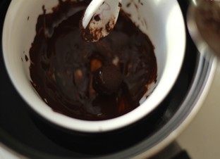 浓情巧克力礼盒,取另外一些黑巧克力，掰成小块。隔水加热并不断搅拌，直到完全溶化。巧克力溶化后从水里取出，冷却至和手心差不多的温度。把18步做好的巧克力软球，放进溶化巧克力里。滚一下，使其表面沾上一层溶化的巧克力，并迅速捞出。