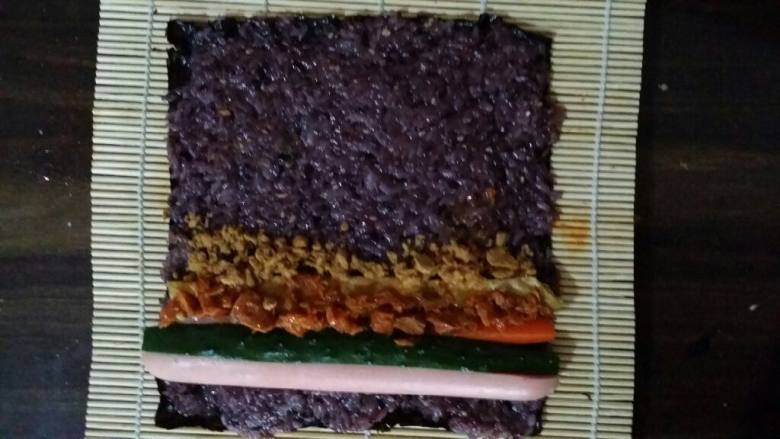 金枪鱼寿司,配料准备好后包就快了。把紫菜摆好铺上一层米。把鸡蛋香肠准备好的配料都摆上。