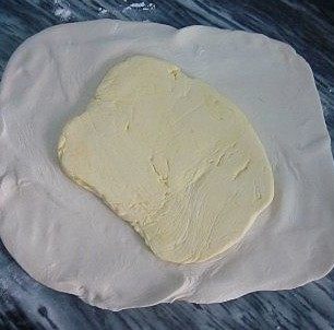 可颂,将冻好的面擀成大方形面的面团，将黄油块放在中间，再将黄油块包裹起来