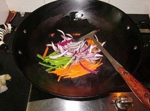 芒果茄汁意大利面,锅内放入适量的油，烧热后，下入切成丝的青椒、洋葱与胡萝卜，大火炒至断生。