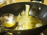 香蒜糖醋鱼,锅内烧些许油至八成热，转中火将鱼放入，用勺子舀起热油不停往暴露在外的鱼身、鱼头、鱼尾上浇热油，无需翻面，将鱼炸透取出放入盘内