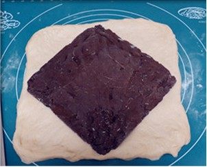 巧克力大理石土司,将面团先擀成牛舌状，翻面擀成25*25CM正方形，把巧克力夹馅从冷冻室取出，菱形状放面团中间。