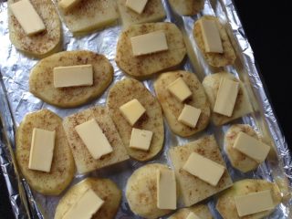 孜然烤土豆片,如图将腌制好的土豆平铺到烤盘上，放上小块黄油