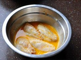 香酥辣鸡翅,将腌好的鸡翅中去除作料，放进打散的鸡蛋中，均匀沾裹上一层鸡蛋液