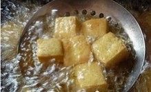可乐豆腐,炒菜锅里倒入食用油，油热以后将豆腐块放入油中，炸至表面微黄捞出