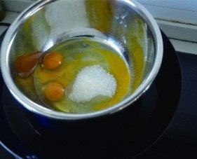 橙香蔓越莓碗糕,鸡蛋磕入打蛋盆，加入白砂糖，隔水加热一会