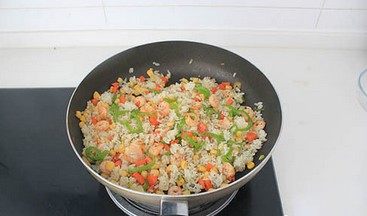 虾仁芝士焗饭,放玉米粒和米饭，调入1大勺黑胡椒碎翻炒均匀，至米饭温热。