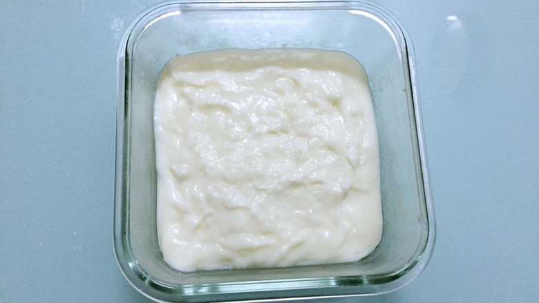 椰丝牛奶小方糕,趁热把牛奶糊倒入保鲜盒中，抹平表面