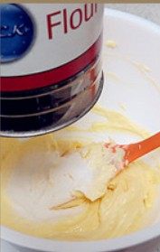 奶香曲奇,把高筋粉、奶粉、玉米淀粉用面粉筛，筛入黄油糊中。用刮刀混合，直到粉和黄油完全混合为止
