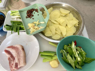 土豆回锅肉,改刀：土豆切两毫米的片，蒜切片，姜一半切丝一半切片，蒜苔拍一拍，切马耳朵段，青红椒切块
